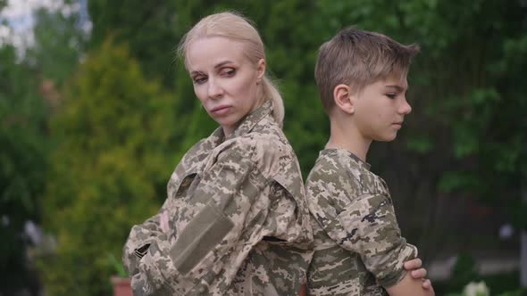 Argued Dissatisfied Military Woman and Teenage Boy in Khaki Camouflage Standing Back to Back