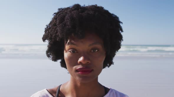 African American woman looking at camera and smiling on the beach and blue sky background