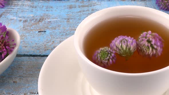 Brewing a tisanes from red clover in a white cup. 