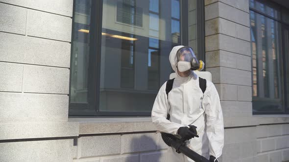 Man in White Full Protected Suit with Disinfectant Clean the Streets