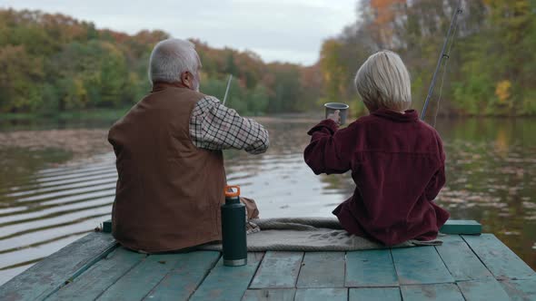 Grandfather and Grandson Drinking Tea and Fishing on Pier