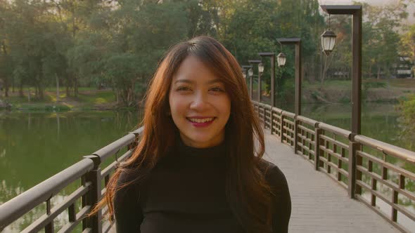 Portrait of a Beautiful Thai Woman on a Bridge in the Park at Sunset