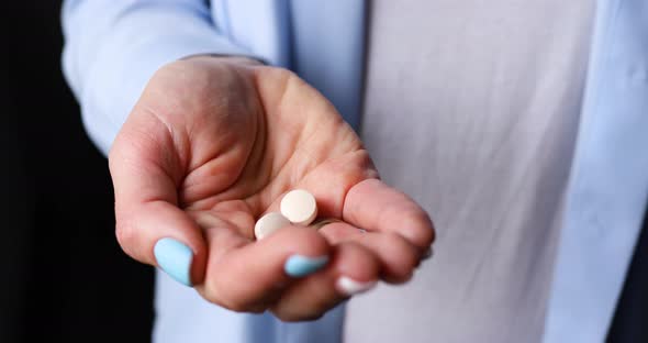 Anonymous woman pour white pills from the meds bottle into the palm of the hand before taking them