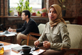 Young pretty businesswoman in hijab sitting by table and looking at camera - PhotoDune Item for Sale