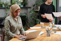 Young serious businesswoman in hijab looking at laptop screen - PhotoDune Item for Sale