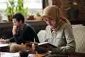 Young serious Muslim businesswoman in hijab looking through notes - PhotoDune Item for Sale