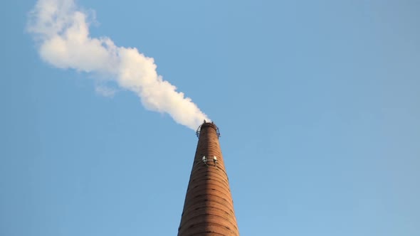 Industrial Pipe Made of Red Brick From Which There Is White Smoke