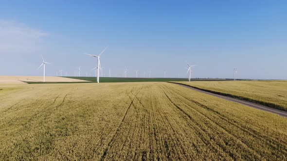 Sliding aerial shot over a dirt road and a wind park in the distance