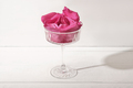 Champagne glass with pink rose petals ice cubes on white table. Details of romantic table setting - PhotoDune Item for Sale