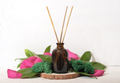 home scent, reed diffuser on wooden podium with green leaves and petals decor.  - PhotoDune Item for Sale