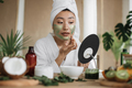 Portrait of young asian woman in towel with green moisturizing cosmetic facial mask  - PhotoDune Item for Sale
