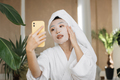 Healthy asian female blogger holding smartphone applying white cotton mask - PhotoDune Item for Sale