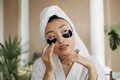 Pleasant asian woman using eye patches for beauty procedures at exotic tropical living room. - PhotoDune Item for Sale