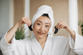 Pleasant asian woman in white bathrobe and towel holding eye patches - PhotoDune Item for Sale