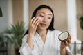 Close up view of face of young asian woman applying natural cosmetics at home - PhotoDune Item for Sale