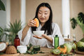 Focus on hands of asian woman preparing cream using orange for skin care sitting at wooden table - PhotoDune Item for Sale