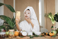Close up portrait of happy asian woman blogger holding phone applying white cotton mask sheet - PhotoDune Item for Sale