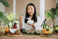 Focus on ingredients for homemade cosmetics lying on wooden table, blurred happy asian woman - PhotoDune Item for Sale