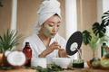 Portrait of young asian woman in towel with green moisturizing cosmetic facial mask - PhotoDune Item for Sale