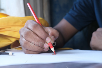 child boy drawing with colored pencil on a page.