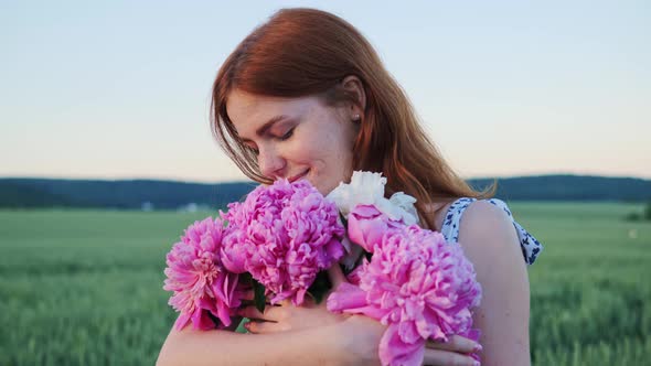 Adorable Beautiful Red Haired with Freckles Holding Pink Flowers in the Field