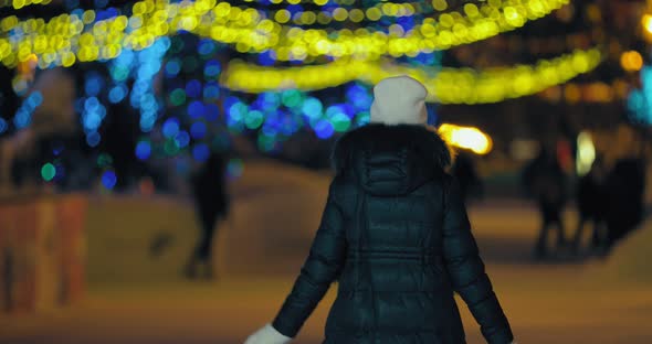 Woman Walks in the Park in Winter in a Jacket and Hat