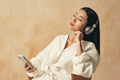 Peaceful asian woman relaxing with closed eyes, listening to meditative music in wireless headphones - PhotoDune Item for Sale