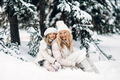 Handsome mother and daughter are having fun outdoor in winter time. Sitting on snow in forest - PhotoDune Item for Sale