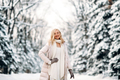Fashion young smiling blonde woman in winter. Standing among snowy trees in winter forest. - PhotoDune Item for Sale