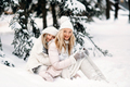 Handsome mother and daughter are having fun outdoor in winter time. Sit in forest between snowy tree - PhotoDune Item for Sale