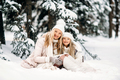 Handsome mother and daughter are having fun outdoor in winter time. Sitting on snow in forest  - PhotoDune Item for Sale