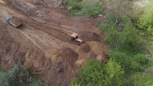 Aerial view of bulldozer flattening surface on further construction site