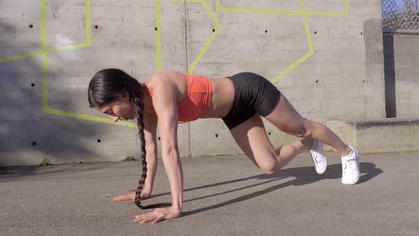 Fit young woman doing mountain climbers abdominal exercise outdoor