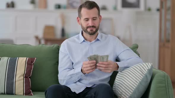 Successful Young Man Counting Dollar at Home