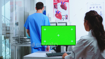 tant holding patient x-ray in hospital cabinet. Desktop with replaceable green screen in medical clinic while doctor is checking patient radiography for diagnose.
