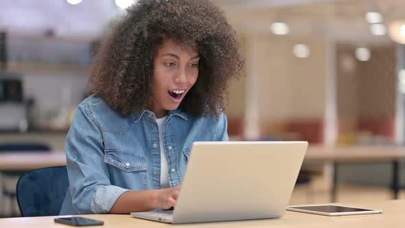 Smiling Young Latin Woman with Laptop Pointing at the Camera