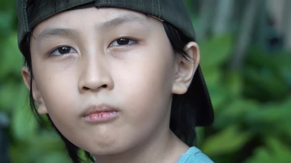 Southeast Asian boy looking cute and cool in slow motion close up out doors looking into the camera.