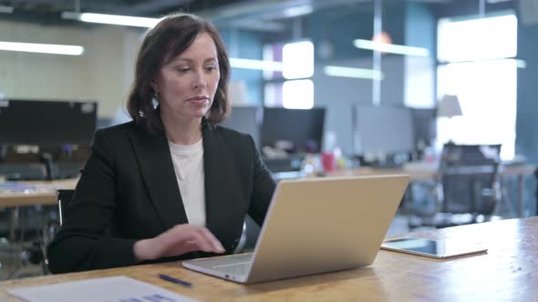 Serious Middle Aged Businesswoman Standing Up and Going Away From Laptop