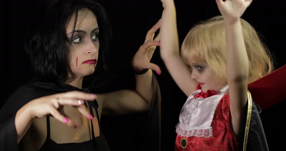 Woman and Child Dracula. Halloween Vampire Make-up. Kid with Blood on Her Face