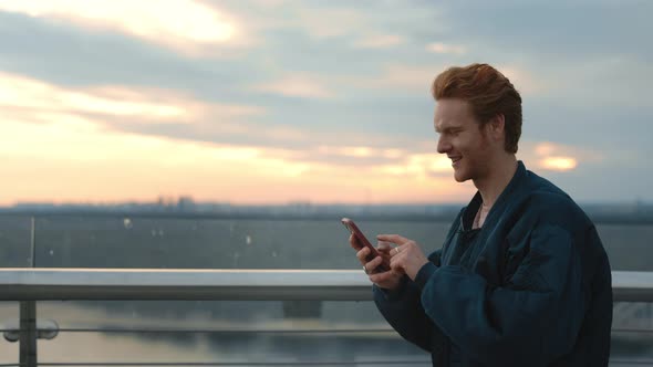 Redhead Guy Texting on Mobile Phone While Walking on Street