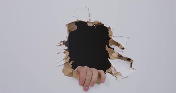 Man Looks Through Big Hole in White Drywall Made with Axe