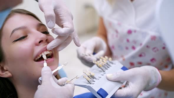 Young female at dentist office. Young lady sitting in dental chair while stomatologist hands