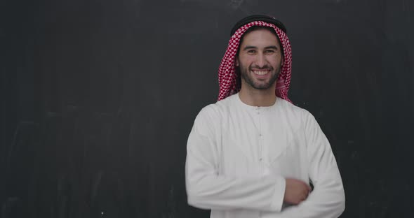 Portrait of Young Arabian Man in Traditional Clothes in Front of Black Chalkboard