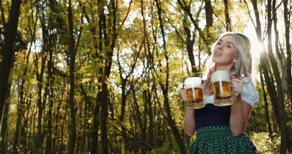 Slavic Woman with Poses with Two Mugs of Beer and Laughs in Autumn Forest