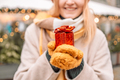 Beautiful excited blonde young woman wearing winter clothes standing showing gift box - PhotoDune Item for Sale