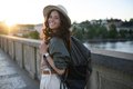 Young beautiful female traveler with backpack walking through bridge on sunny day in city. - PhotoDune Item for Sale