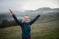 Senior woman doing breathing exercise in nature on early morning with fog and mountains in - PhotoDune Item for Sale