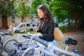 Businesswoman with bike sitting and using smartphone. Commuting and alternative transport concept - PhotoDune Item for Sale