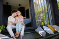 Young couple sitting and cuddling in hammock terrace in their new home in tiny house in woods - PhotoDune Item for Sale