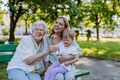 Worried senior grandmother comforting grown up granddaughter when sitting on bench in park, share - PhotoDune Item for Sale